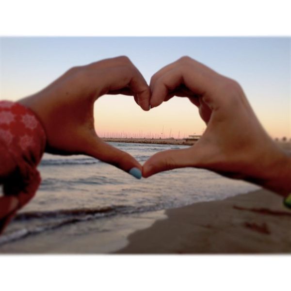 символ любви из рук на фоне моря